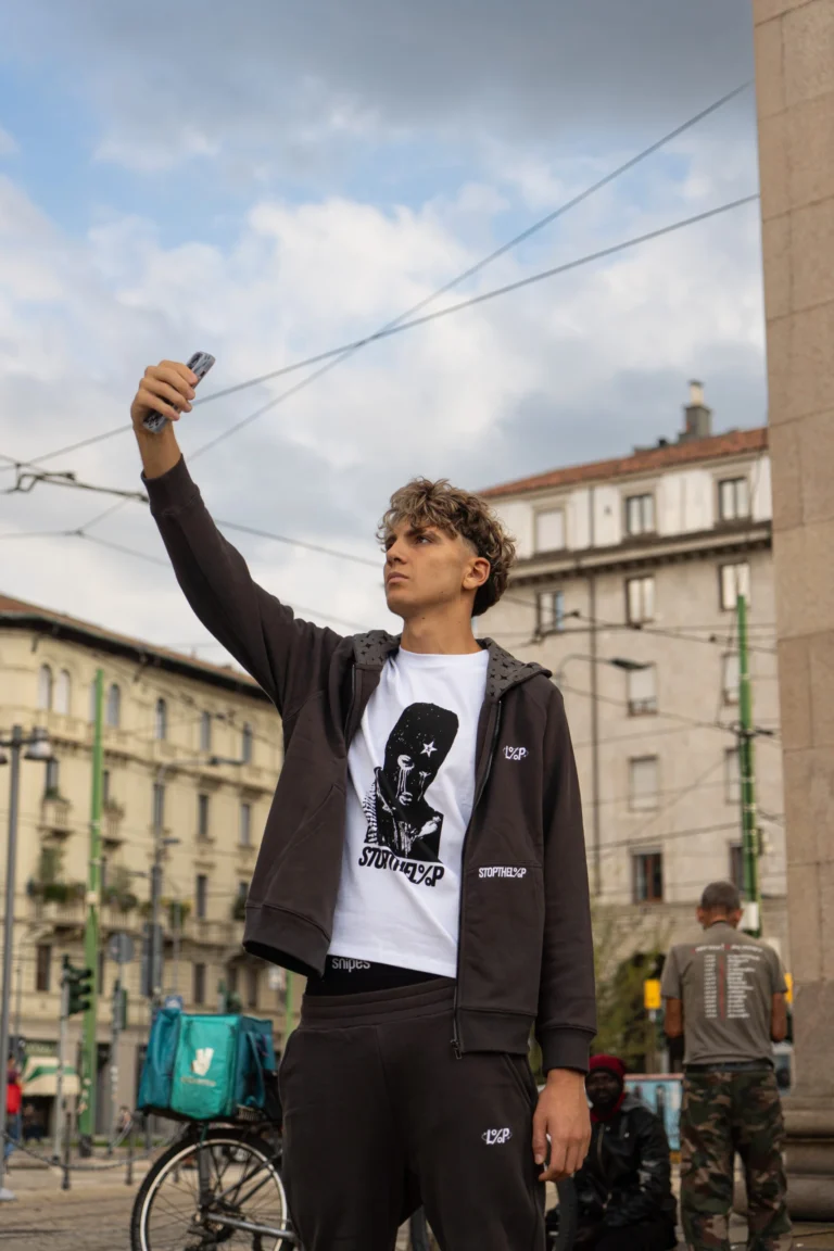 Model holding up the Bandit Tee over a Stars Hoodie, Milan street
